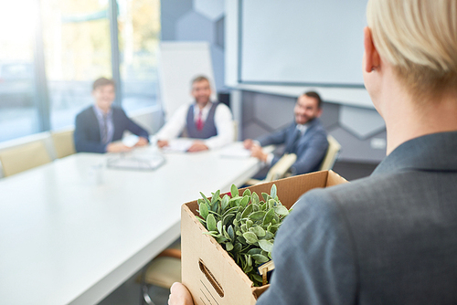 Rear view of unrecognizable young woman holding box of personal belongings coming to business interview in board room, copy space