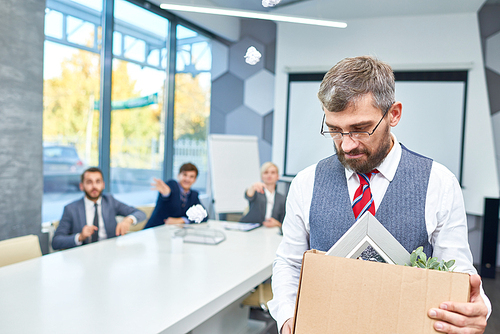 Portrait of depressed mature businessman holding box of personal belongings being fired from work in company, copy space