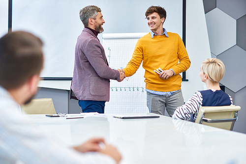 Portrait of young businessman presenting marketing report shaking hands with boss at the end of meeting