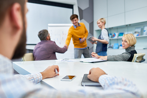 Group of business people shaking hands after successful presentation, focus on foreground, audience point of view