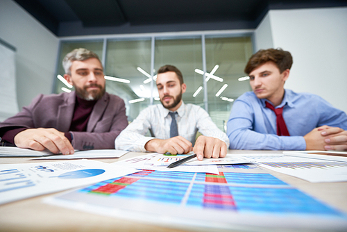 Low angle view of confident financial managers gathered together at meeting room and analyzing financial figures, focus on foreground