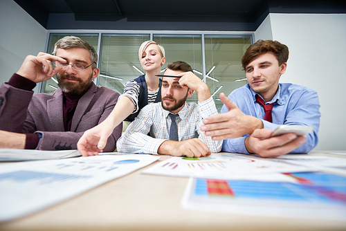 Portrait of three business people sitting at meeting table discussing financial problems analyzing financial and marketing statistics for annual report