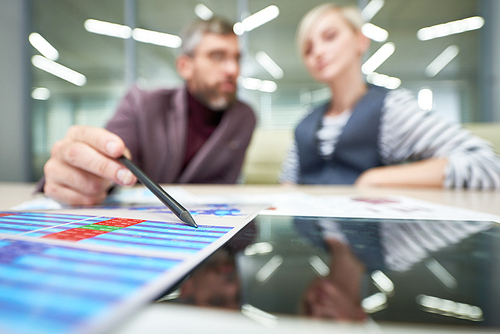 Two business people discussing financial documents with data in office, focus on foreground, copy space