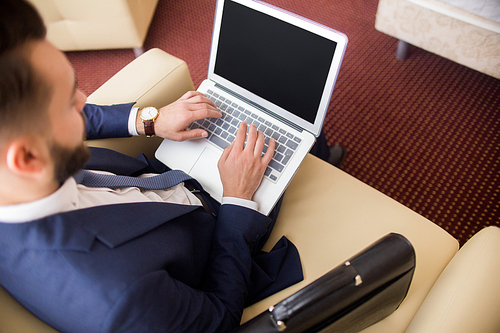 High angle of successful businessman using laptop working in hotel room or lobby, copy space