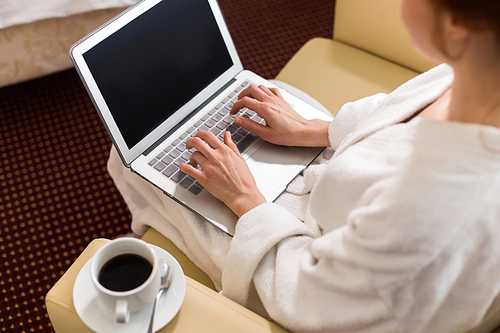 High angle of unrecognizable businesswoman dressed in bathrobe working with laptop  in hotel room enjoying business travel, copy space