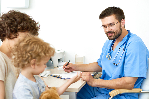 Portrait of smiling doctor talking to little boy in appointment