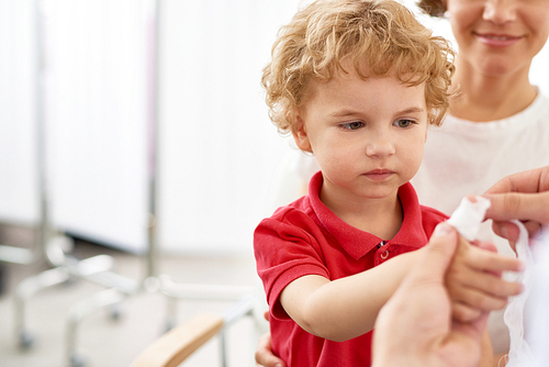 Portrait of adorable little boy with mother visiting doctor to bandage hurt finger, copy space