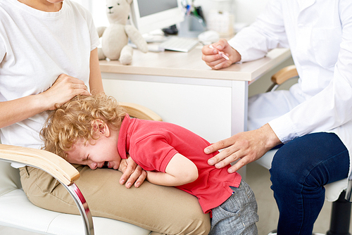 Portrait of little boy throwing hysterical tantrum at doctors office  refusing to be vaccinated