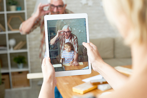Portrait of little boy with his grandpa posing for photo taken via digital tablet, image on screen