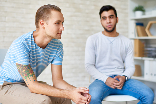 Support group sitting in circle and sharing their problems with other members during productive therapy session at cozy psychologists office