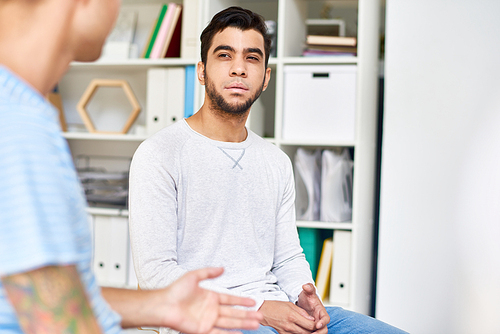 Group of young patients participating in group therapy session for training social skills, interior of cozy psychologists office on background