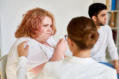Portrait of  crying obese  woman talking to psychiatrist during group therapy session, providing counseling and support on mental issues