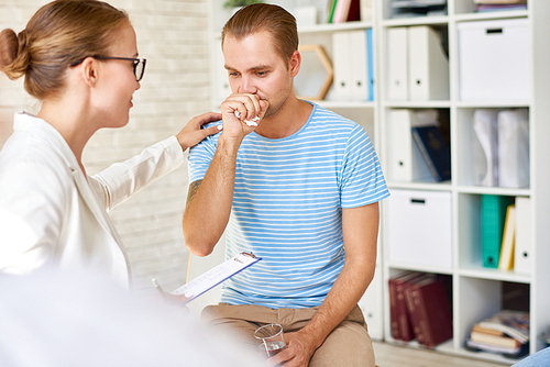 Talented young psychiatrist sitting in circle while comforting member of rehab group at therapy session