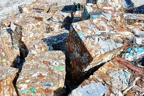 Background image of trash blocks at modern recycling factory, lit by sunlight, copy space