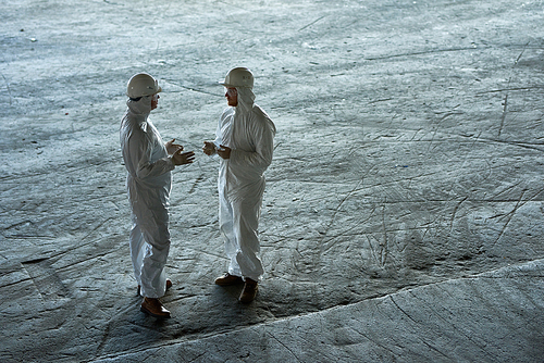 Full length portrait of two workers wearing protective suits standing in empty workshop of waste processing plant, copy space