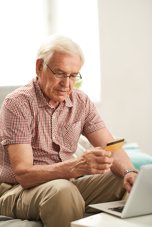 Portrait of senior man online shopping holding credit card for payment