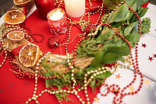 Close-up shot of Christmas decor on wooden table: handmade wreath and candles