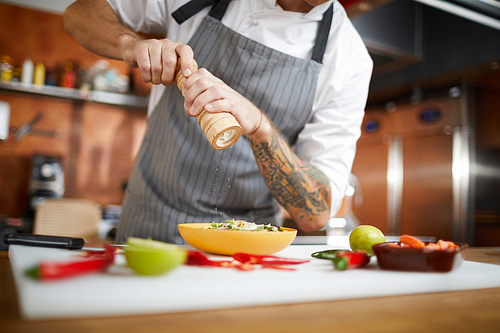 Mid section portrait of professional chef salting dish while cooking in restaurant kitchen, copy space