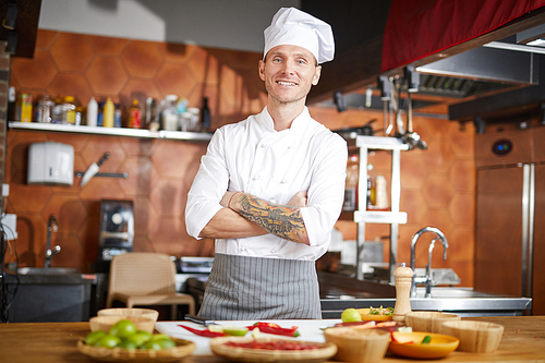 Waist up portrait of handsome chef posing in kitchen standing with arms crossed, copy space
