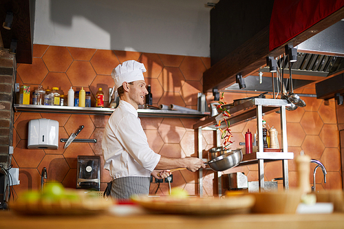 Side view portrait of handsome professional chef cooking in restaurant kitchen, copy space