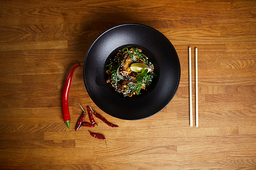 Top view background image of Asian spiced noodles on wooden table with chili peppers, copy space