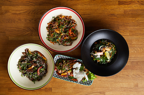 Top view of several Asian food dishes on wooden background, copy space