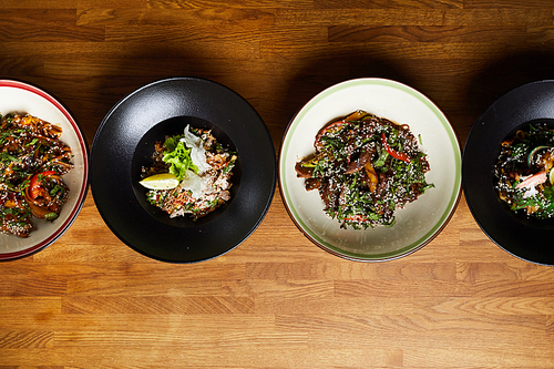 Top view of several Asian food dishes in row on wooden background, copy space