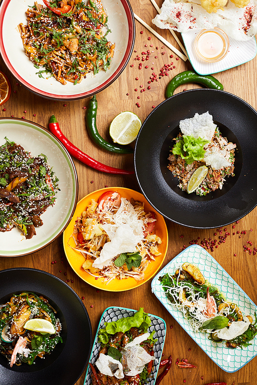 Above view composition of several Asian food dishes on wooden background, copy space