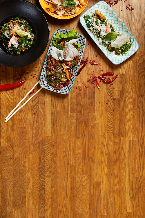 Above view background composition of several Asian food dishes on wooden table, copy space