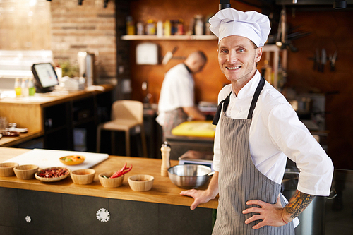 Waist up portrait of professional chef posing in restaurant kitchen nest to Asian food dishes, copy space