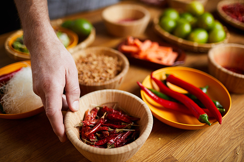 Close up of unrecognizable man holding chili peppers bowl while cooking spicy food, copy space
