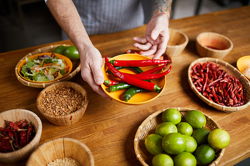 Close up of professional chef holding chili peppers and spices while cooking in restaurant kitchen, copy space