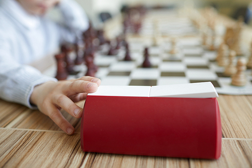 Hand of schoolboy in white shirt pressing chess clock after making chess move in chess game