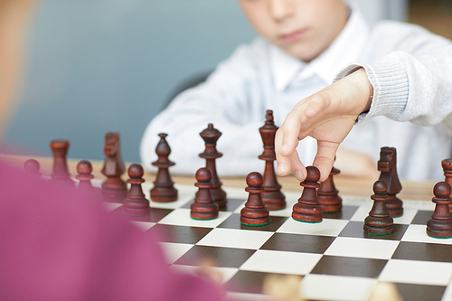 Schoolboy in white shirt making retaliatory move in chess game with girl in purple sweater