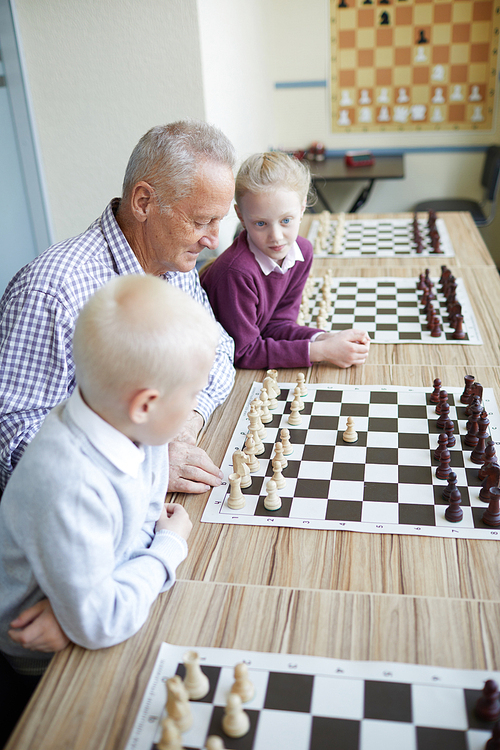 Enthusiastic grandfather showing his two grandchildren famous winning chess combination