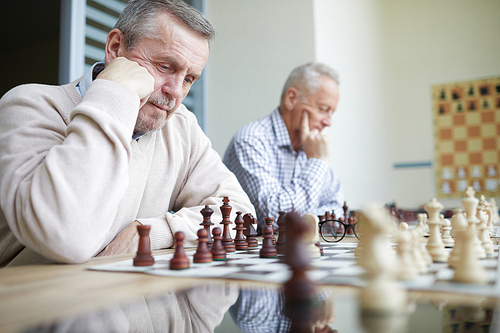 Two experienced aged chess players with silver hair trying to solve difficult chess problems