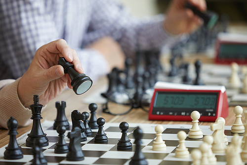 Two chess players sitting in a row and making synchronous chess move with black figures