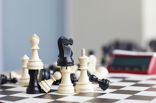 Wooden chess pieces standing one on another like small towers on black and white chess board