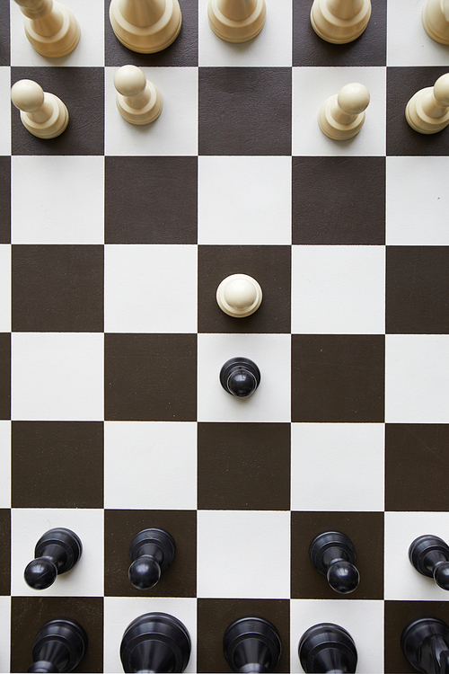 View from above on black and white wooden chess pieces standing on chess game board