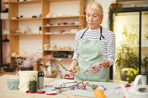 Waist up portrait of mature woman creating flower compositions in art studio, copy space