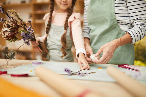 Mid section portrait of mother and daughter creating flower compositions in art studio, copy space