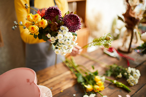 Closeup of unrecognizable florist arranging bouquets in cozy flower shop, copy space