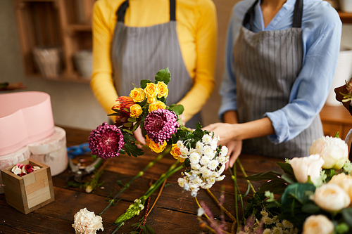 Crop portrait of two unrecognizable florists holding beautiful bouquets at counter in flower shop, copy space