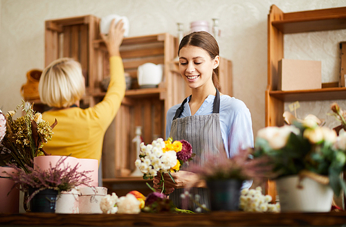 Waist up portrait of smiling young woman working in flower shop, copy space