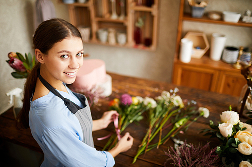 High angle portrait of female florist  and smiling while working in flower shop, copy space