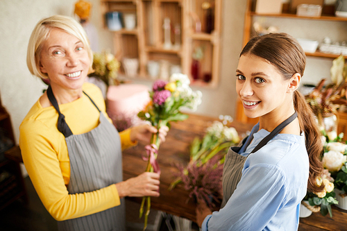 High angle portrait of two female florists  and smiling while working in flower shop, copy space