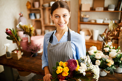 Waist up portrait of female florist  and smiling while working in flower shop, copy space