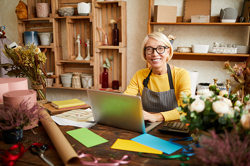 Portrait of smiling female small business owner using laptop and  in flower shop, copy space