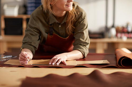 Close up portrait of female artisan working with leather in workshop, copy space