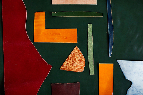 Abstract background of colored leather pieces laid out over textile in design shop, copy space